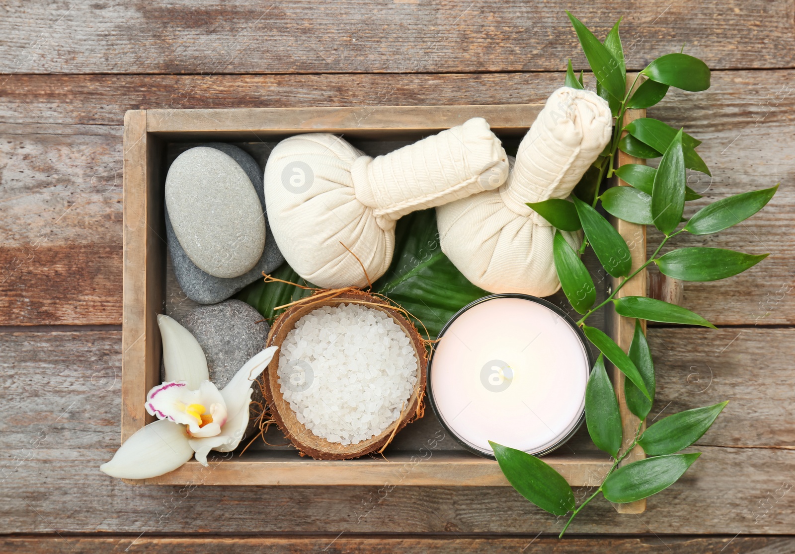 Photo of Box with spa cosmetics, accessories and orchid on wooden background