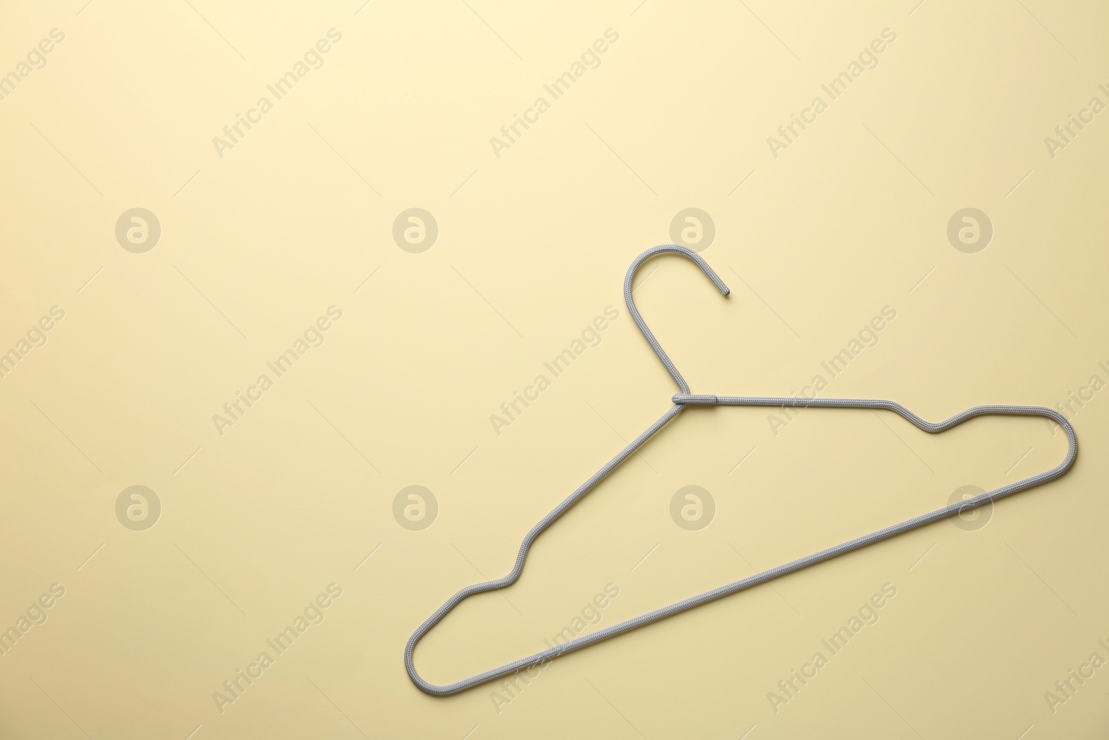 Photo of Hanger on pale yellow background, top view. Space for text