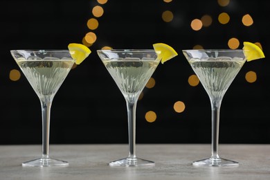 Martini glasses of refreshing cocktails with lemon slices on light grey table