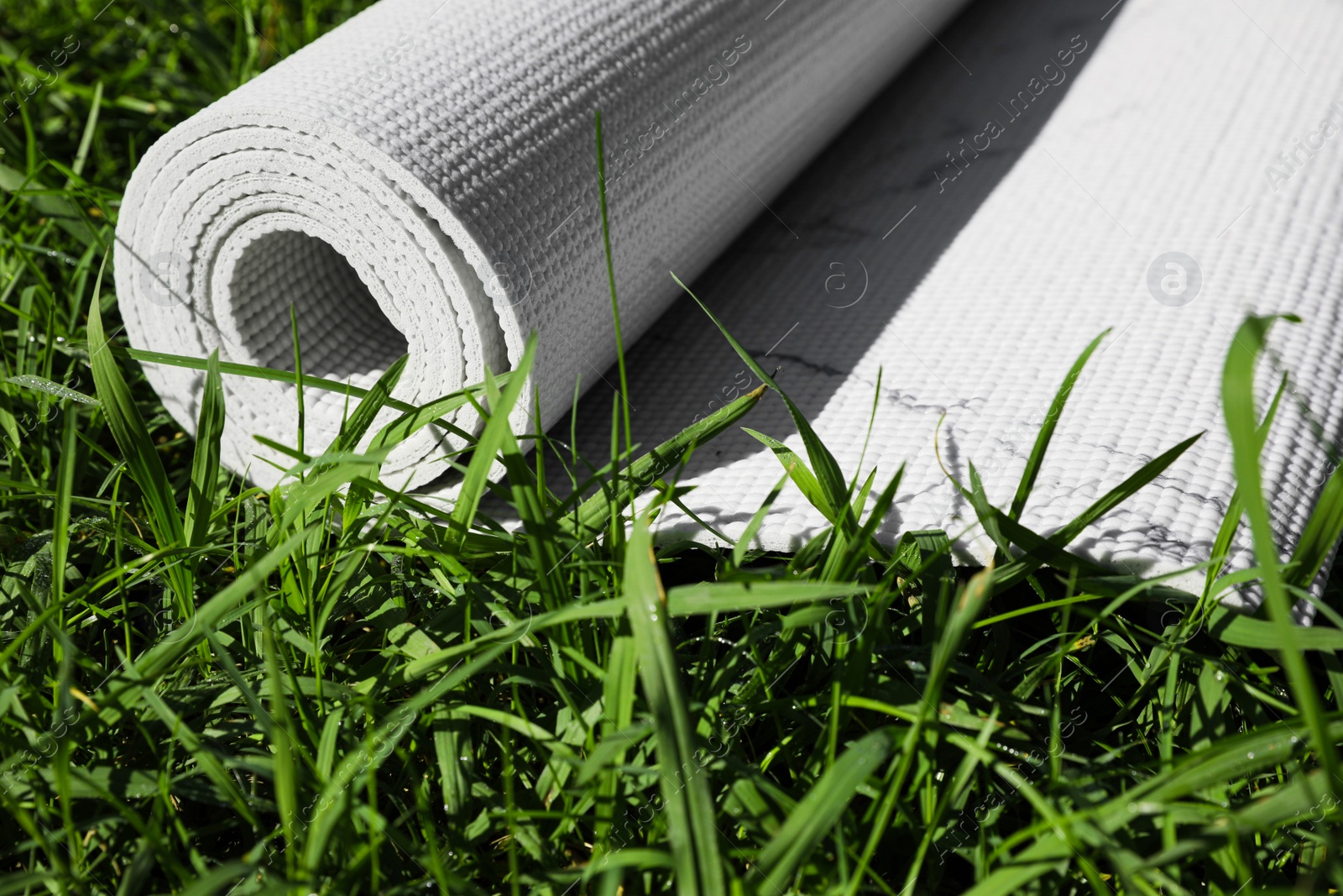 Photo of Karemat or fitness mat on green grass outdoors, closeup