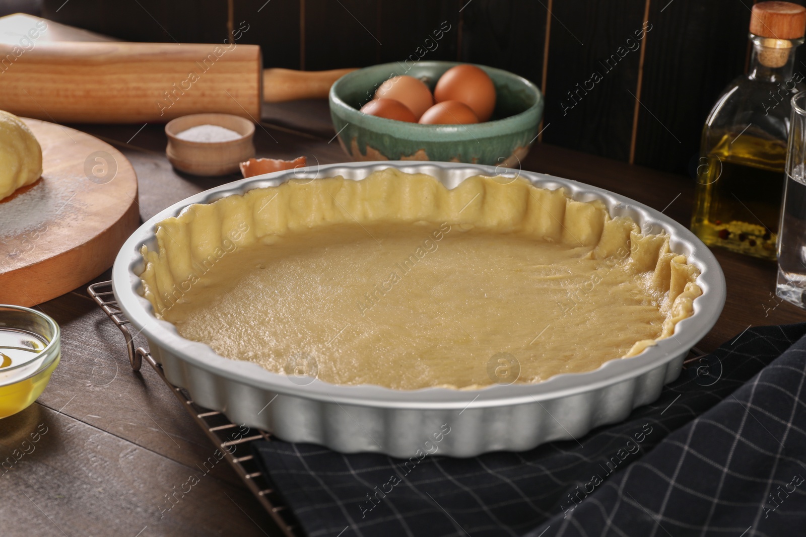 Photo of Pie tin with fresh dough and ingredients on wooden table. Making quiche