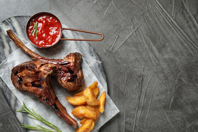 Delicious grilled ribs served on grey table, top view. Space for text