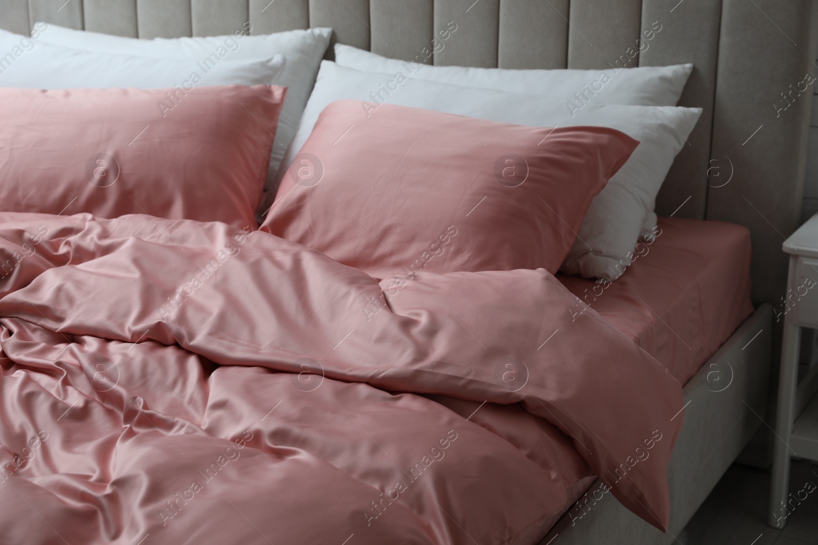 Photo of Bed with beautiful pink silk linens indoors