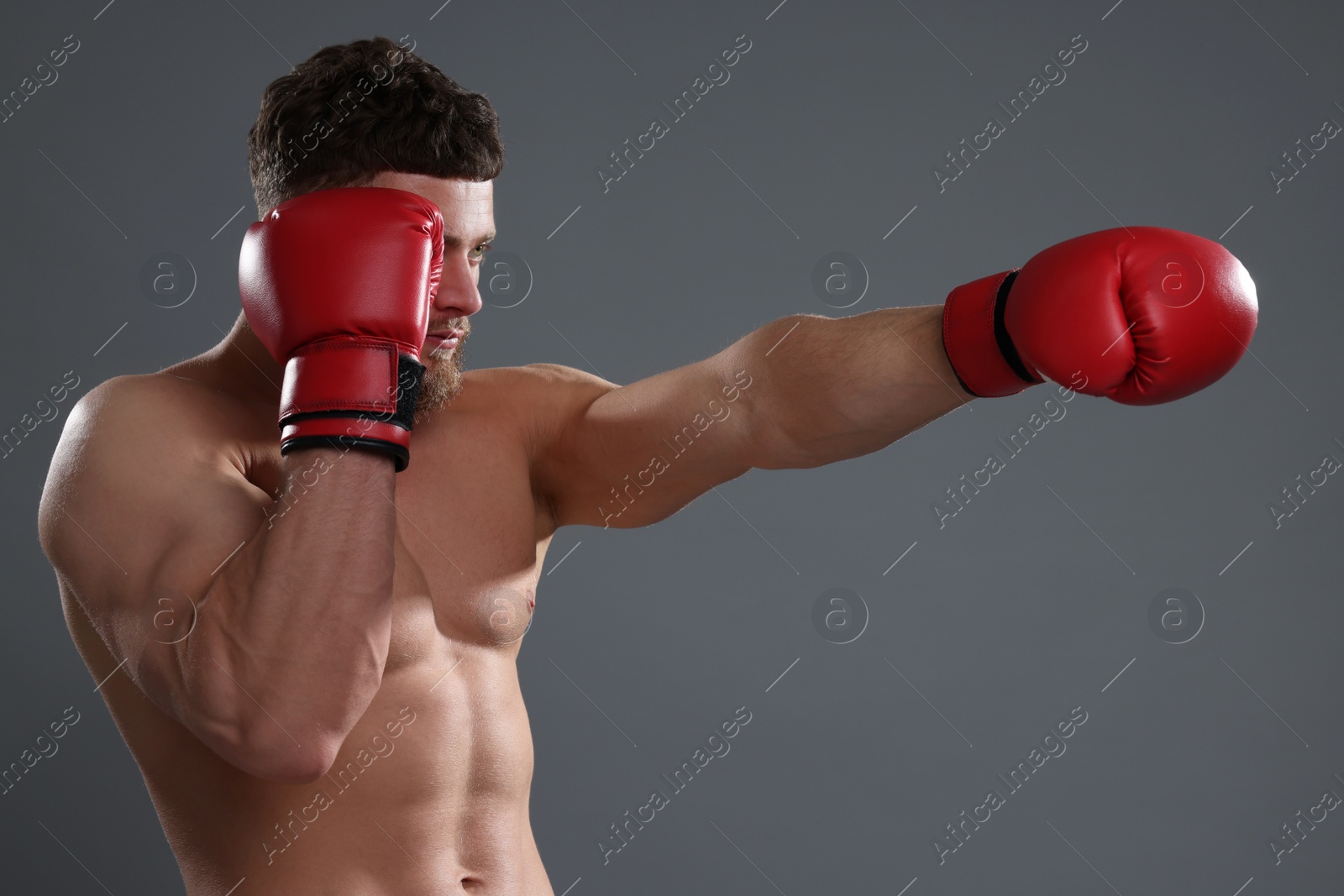 Photo of Man in boxing gloves fighting on grey background