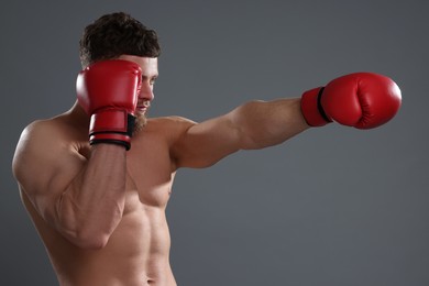 Man in boxing gloves fighting on grey background