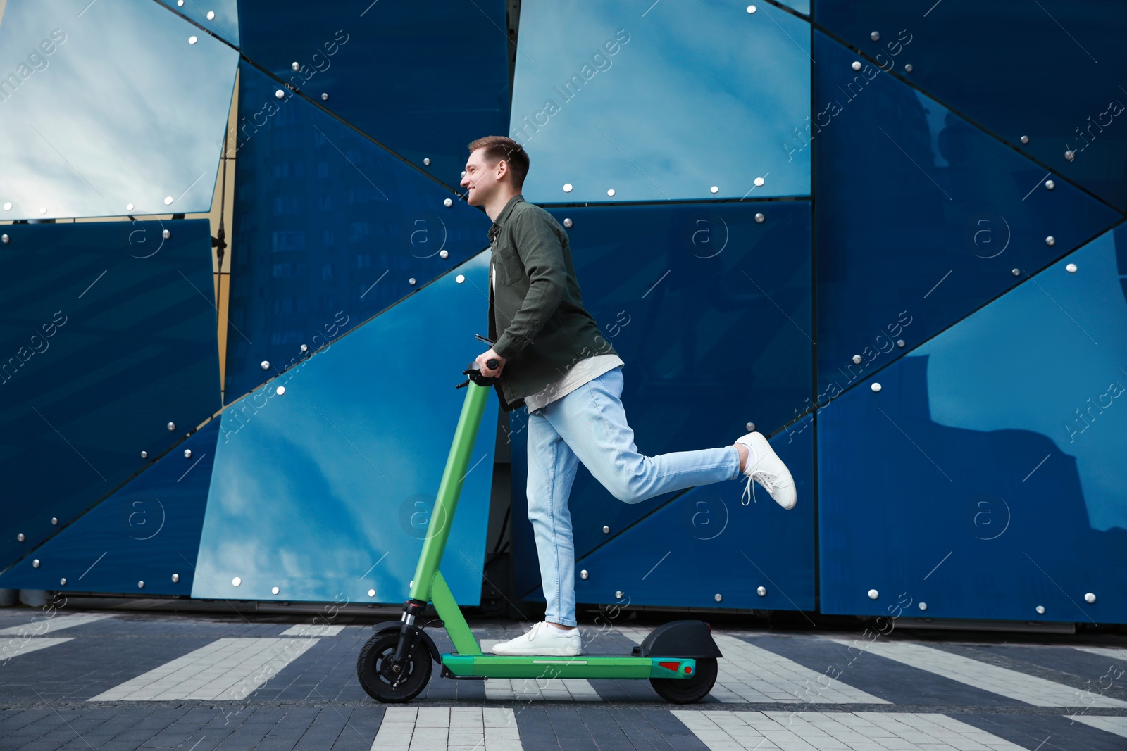 Photo of Happy man riding modern electric kick scooter on city street