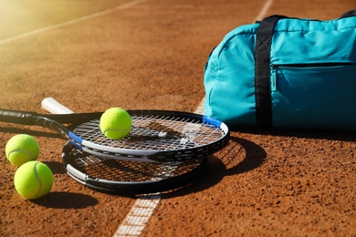 Photo of Tennis balls, rackets and bag on clay court