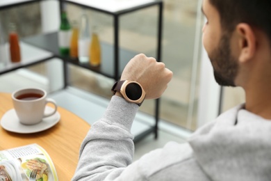 Photo of Man looking at smart watch in cafe