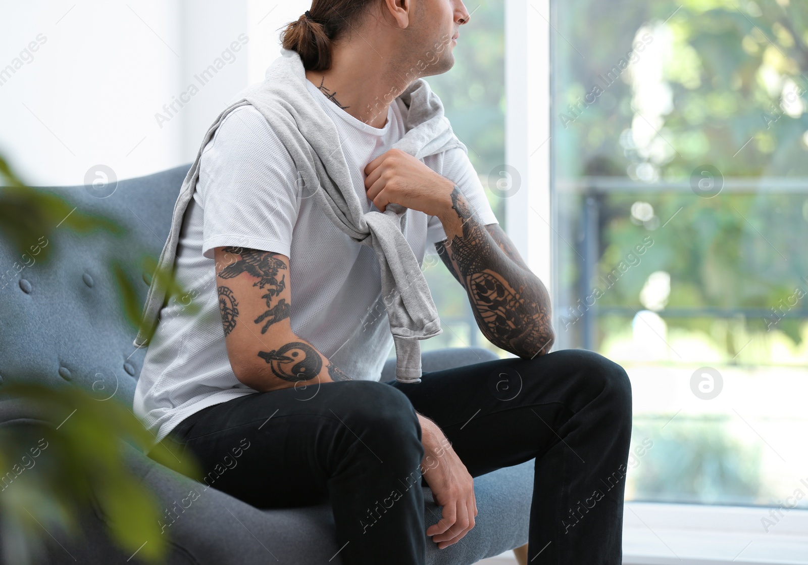 Photo of Young man with stylish tattoos at home