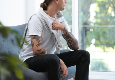 Young man with stylish tattoos at home