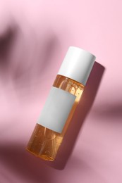 Photo of Bottle of cosmetic oil on pink background, top view