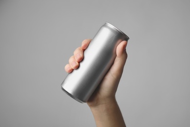 Woman holding aluminum can with beverage on grey background, closeup. Space for design