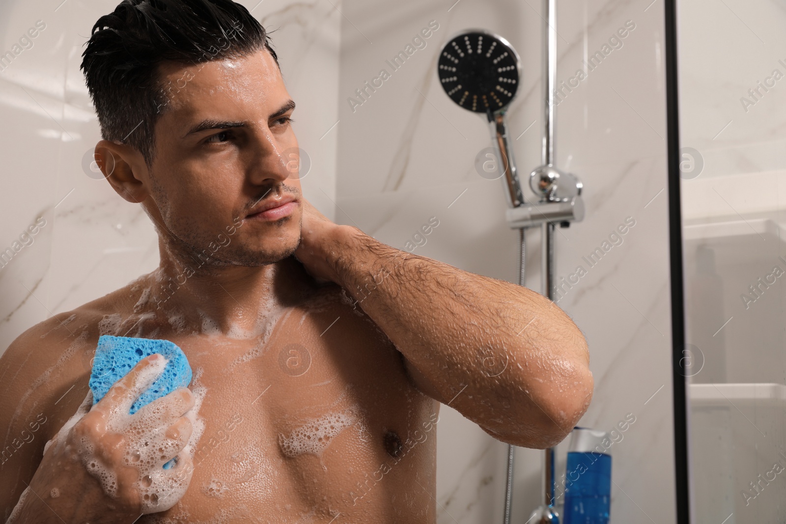 Photo of Handsome man with sponge taking shower at home