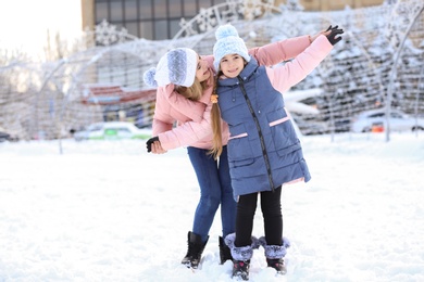 Photo of Portrait of cute little girl with mother outdoors on winter day