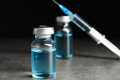 Photo of Vials and syringe on grey table. Vaccination and immunization