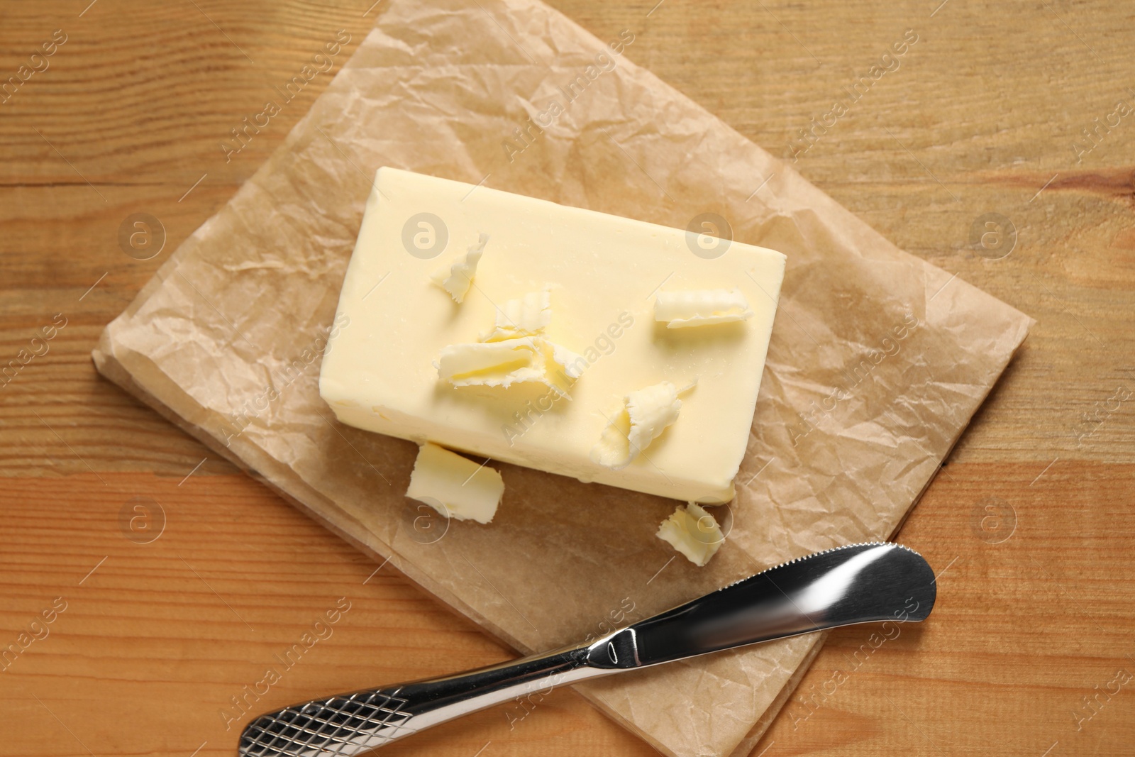 Photo of Tasty butter and knife on wooden table, top view