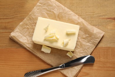 Tasty butter and knife on wooden table, top view