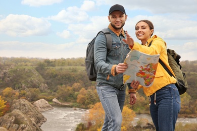 Photo of Couple of travelers with backpacks and map enjoying beautiful view near mountain river. Autumn vacation