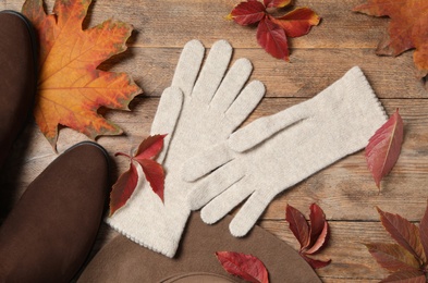 Photo of Flat lay composition with stylish beige woolen gloves and dry leaves on wooden table