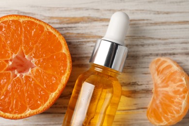 Bottle of tangerine essential oil and fresh fruit on white wooden table, flat lay