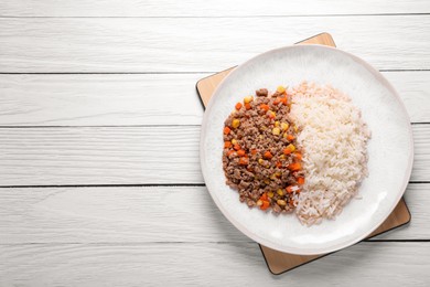 Photo of Tasty dish with fried minced meat, rice, carrot and corn on white wooden table, top view. Space for text