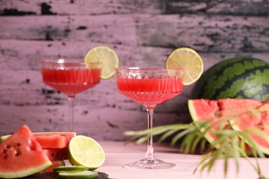 Photo of Cocktail glass of delicious fresh watermelon juice with lime on light wooden table