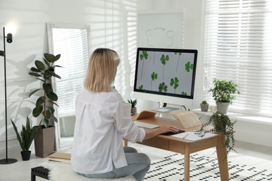 Photo of Woman working at table in light room, back view. Home office