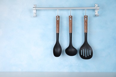 Photo of Rack with kitchen utensils hanging on light blue wall