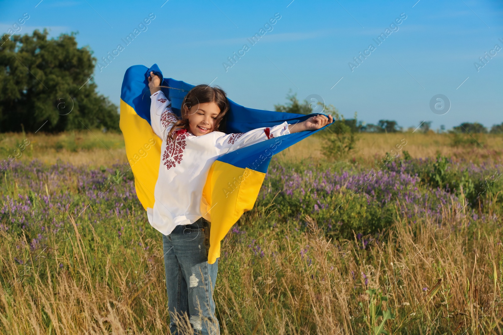 Photo of Happy girl with national flag of Ukraine in field