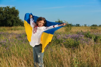 Photo of Happy girl with national flag of Ukraine in field