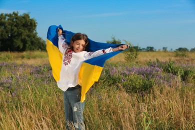 Happy girl with national flag of Ukraine in field