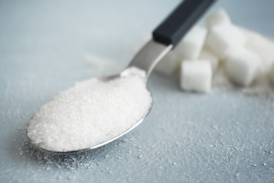 Photo of Spoon with white sugar on gray background