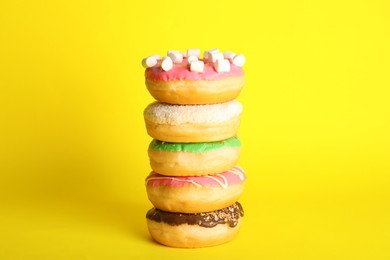 Photo of Stacked sweet tasty glazed donuts on yellow background