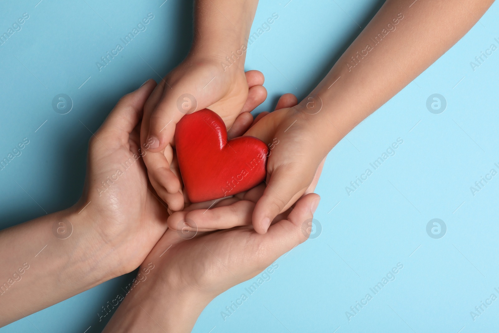 Photo of Woman and child holding heart on blue background, top view with space for text. Donation concept