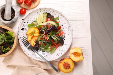 Photo of Delicious salad with vegetables and peach served on white wooden table, flat lay
