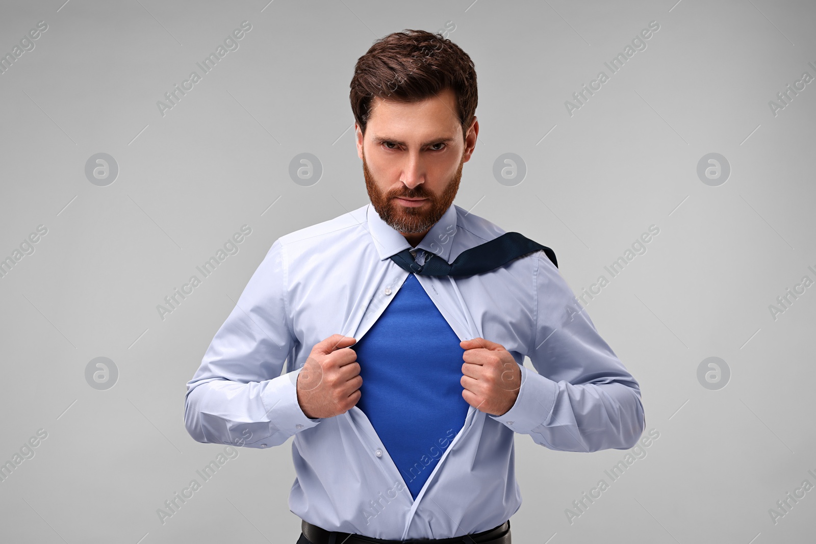 Photo of Confident businessman wearing superhero costume under suit on beige background