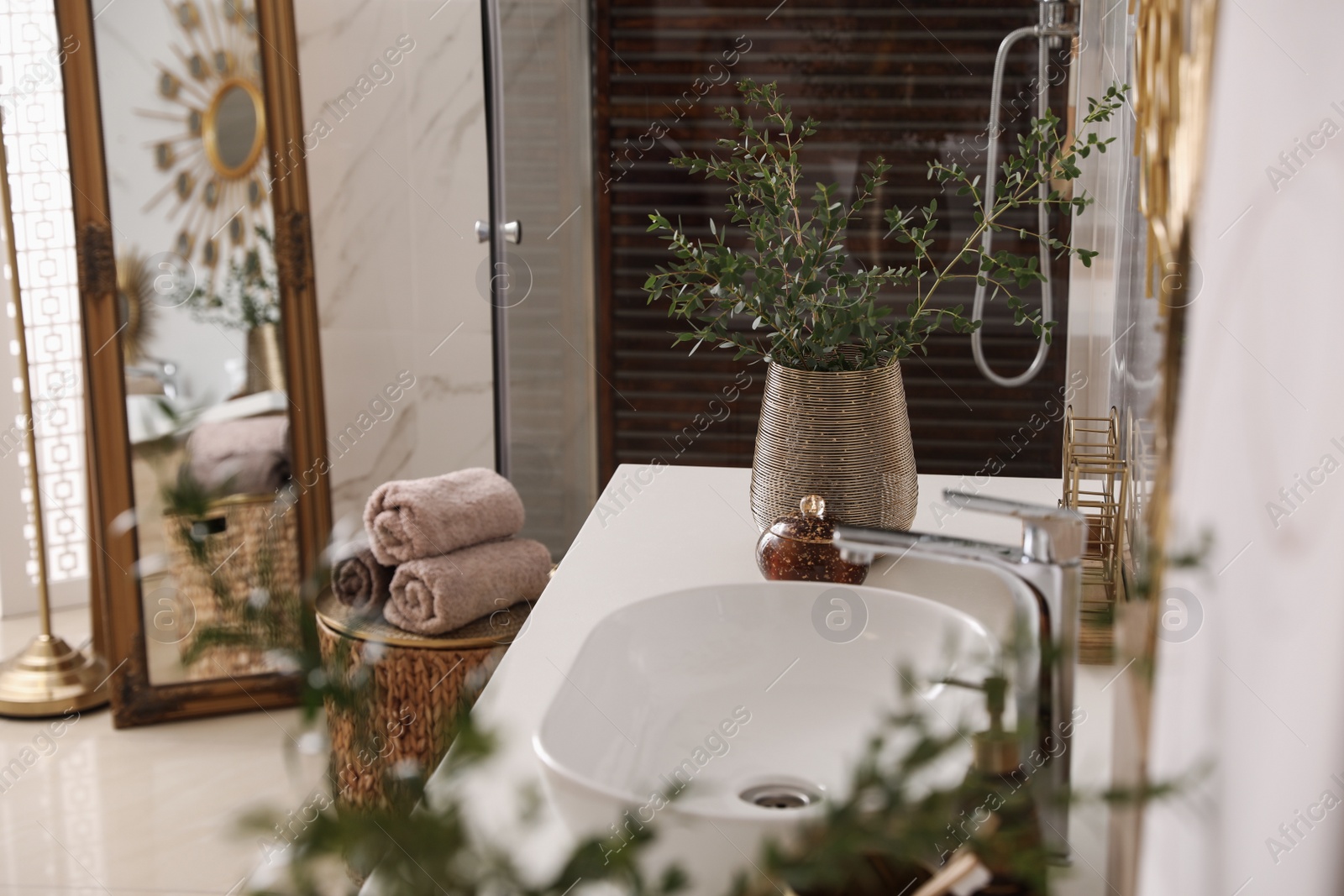 Photo of Vase with beautiful branches near vessel sink in bathroom. Interior design