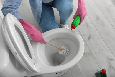 Woman cleaning toilet bowl in bathroom