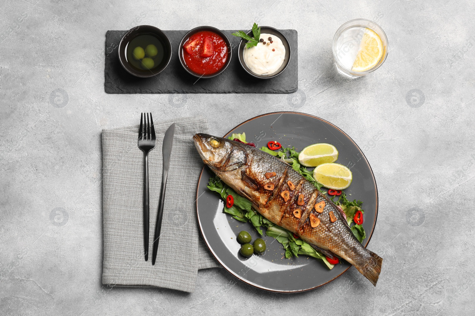 Photo of Flat lay composition with delicious sea bass fish, sauces and ingredients served on light grey table