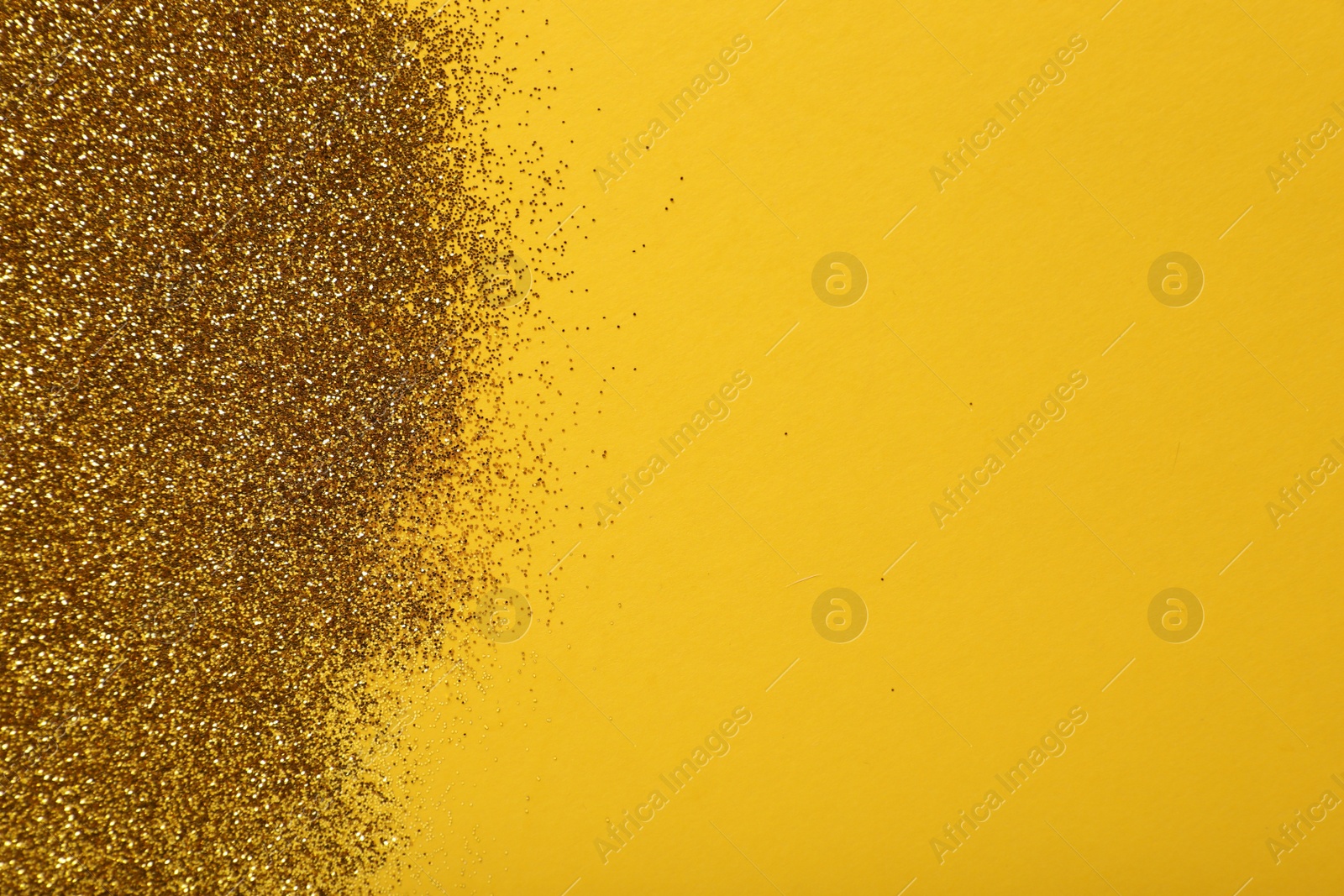 Photo of Shiny golden glitter on yellow background, top view. Space for text