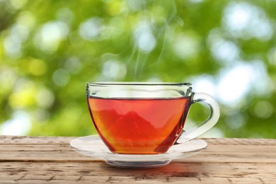 Image of Cup of hot freshly brewed rooibos tea on wooden table outdoors