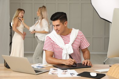 Photo of Professional retoucher working with graphic tablet at desk in photo studio