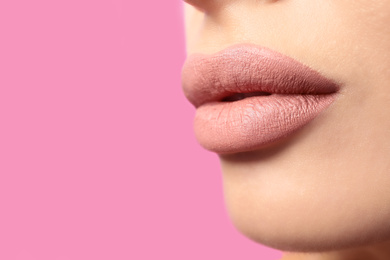 Photo of Woman with matte lipstick on pink background, closeup. Space for text