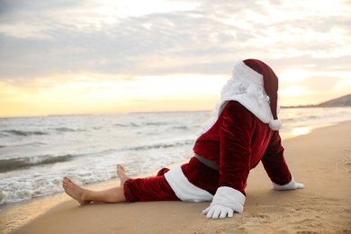 Photo of Santa Claus relaxing on beach, space for text. Christmas vacation