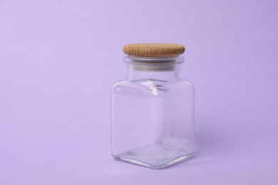 Photo of Closed empty glass jar on lilac background