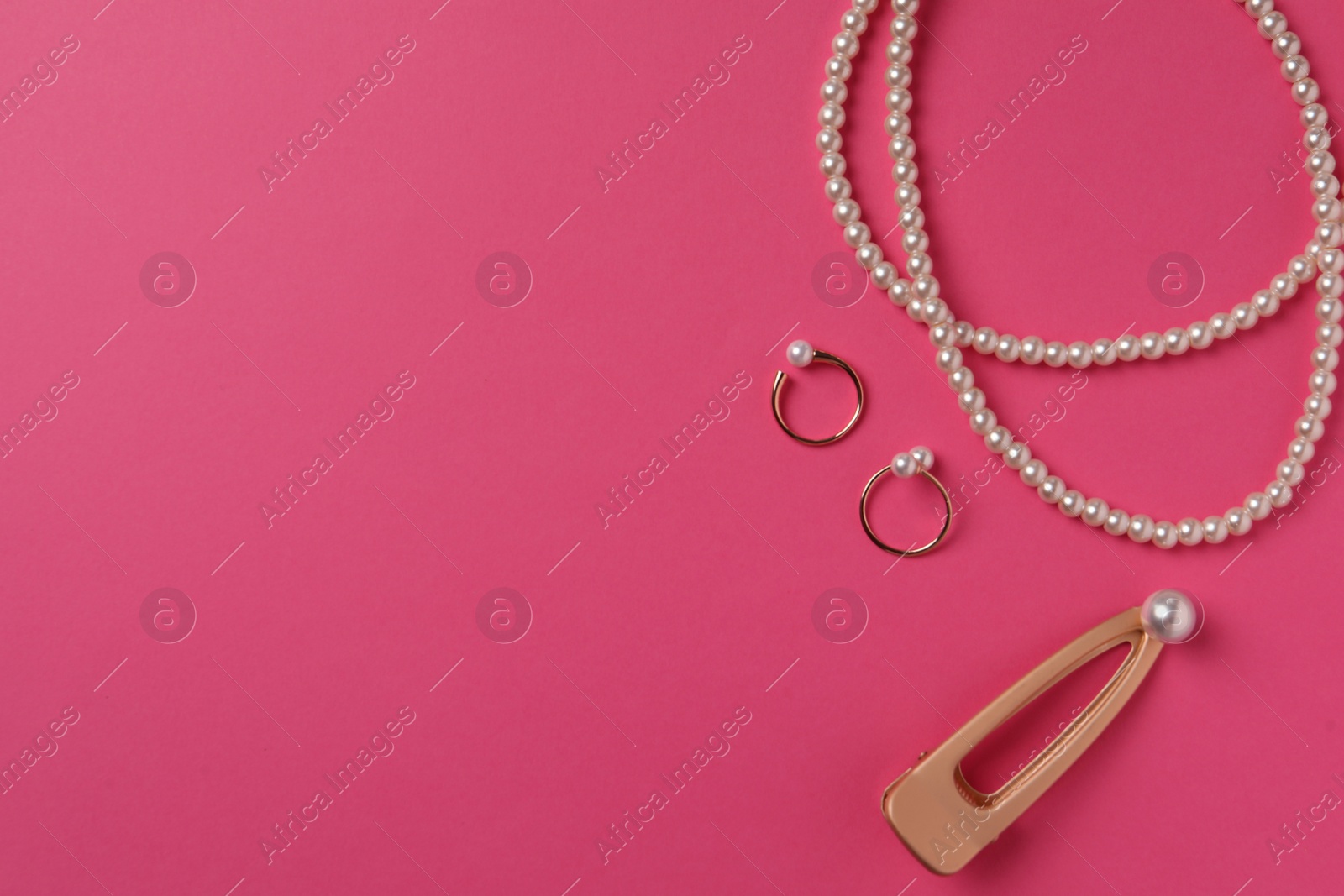 Photo of Elegant necklace, hair clips and rings with pearls on pink background, flat lay. Space for text