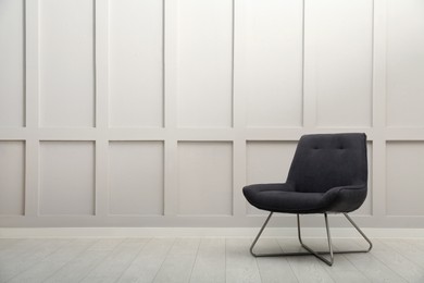 Photo of Modern grey armchair near white wall indoors. Space for text