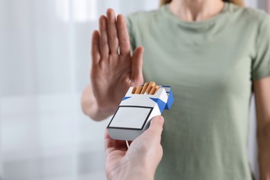 Woman refusing cigarettes on light background, closeup. Quitting smoking concept