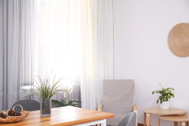 Stylish table near window with elegant curtains in room