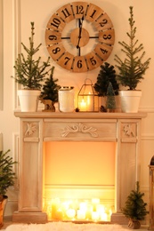 Photo of Beautiful room interior with decorative fireplace and potted fir trees. Christmas decor